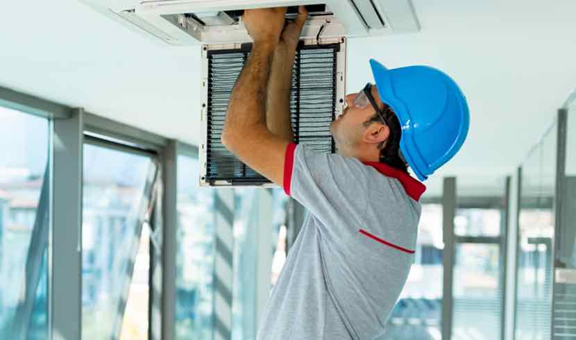 worker reaching into open ceiling access panel